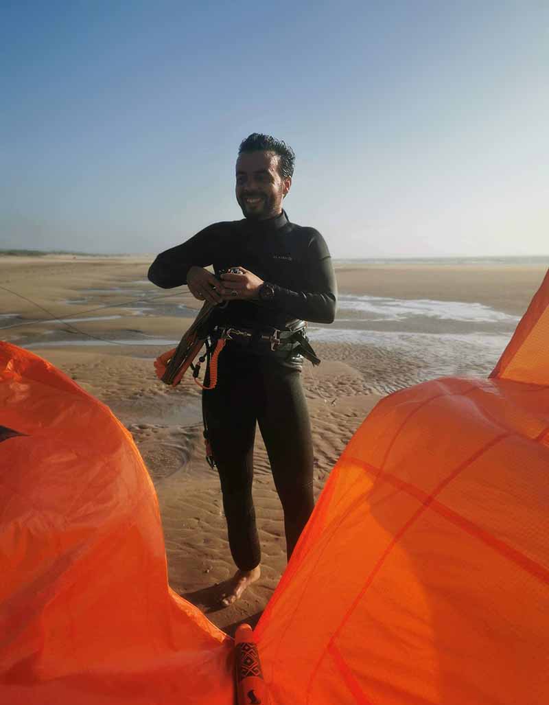 Instructeur de kitesurf qui range les lignes de son aile orange.