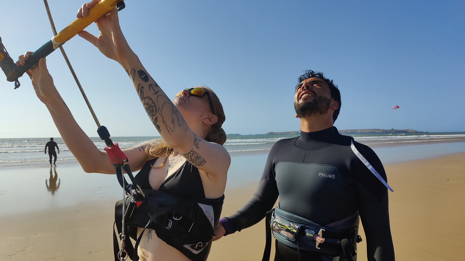 Débutante concentrée sur le maniement de son aile de kitesurf, encadrée par son coach.