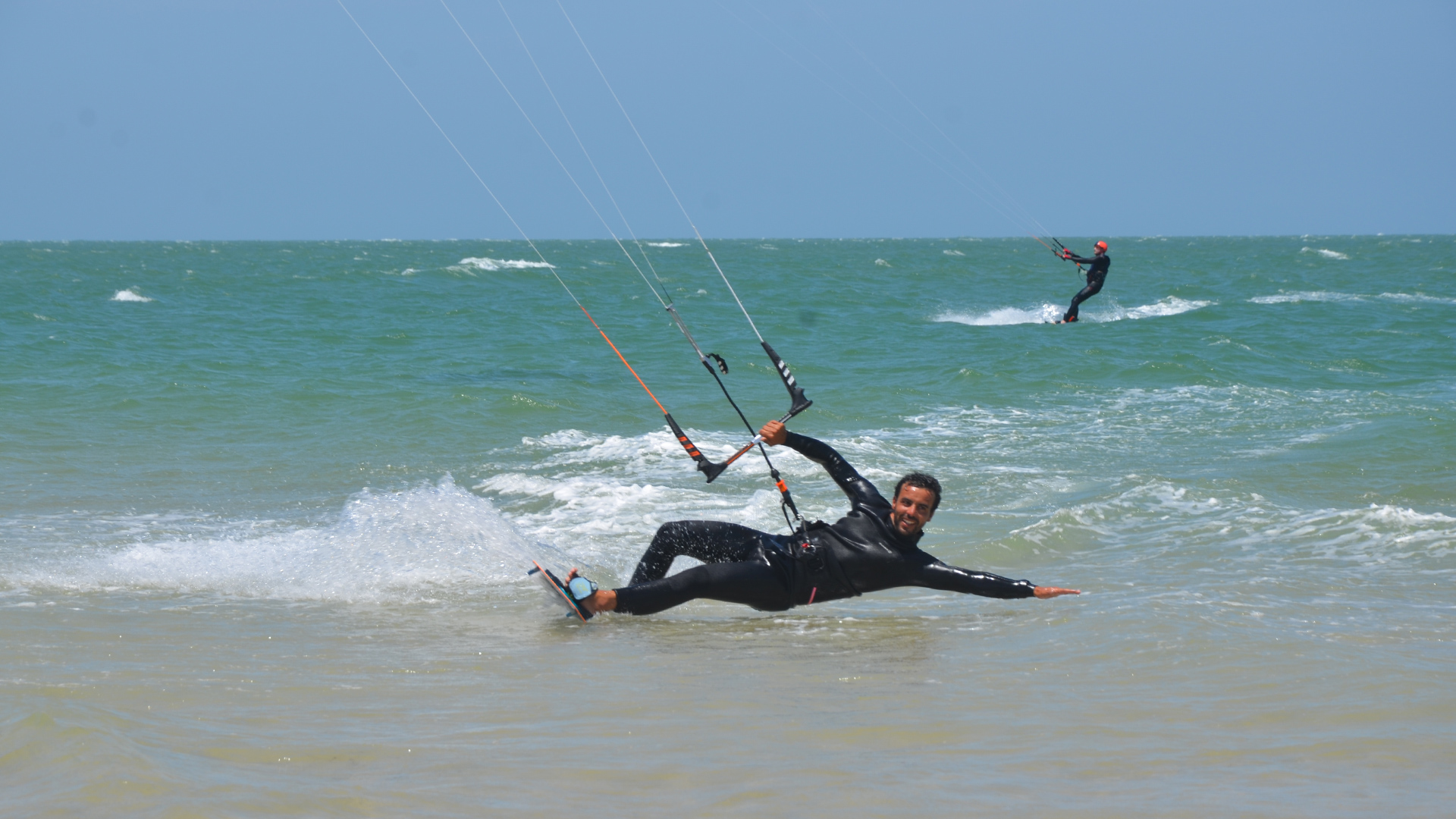 Instructeur de kitesurf qui rase l'eau avec le sourire.